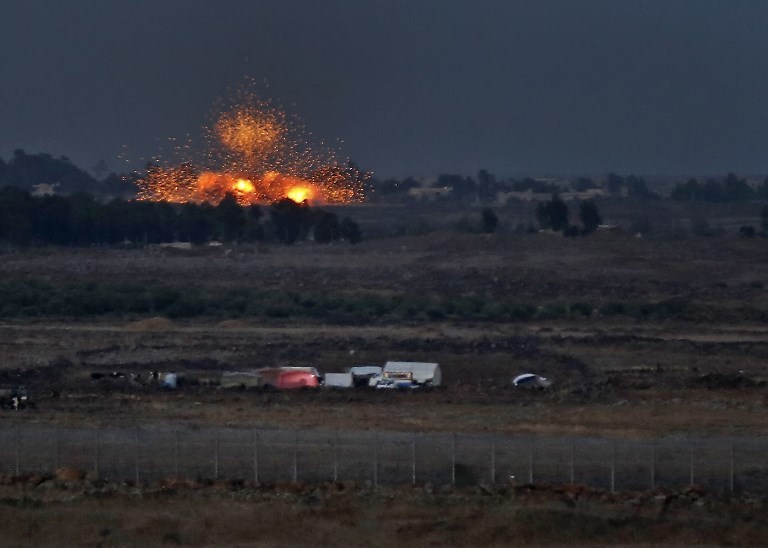 A picture taken on July 24, 2018 from the Tal Saki hill in the Israeli-annexed Golan Heights shows an explosion caused by aerial bombardment across the border in Syria, during air strikes backing a Syrian-government-led offensive in the southwestern province of Daraa. / AFP PHOTO / JALAA MAREY